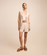 Short clochard de tiro alto confeccionado en viscolino con rayas verticales en tonos beige y blanco, con pliegues en la cintura, trabillas y un cinturón de ráfia con hebilla circular de madera.