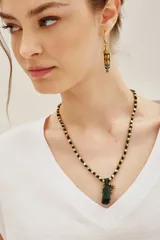 Collar largo con diseño de cuentas doradas intercaladas en un cordón negro, finalizado con una borla negra central.