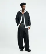Pantalón de jean estilo baggy balloon, de corte holgado con volumen en las piernas y cintura fija con trabillas. Presenta costuras a contratono y detalle de cadena metálica lateral.