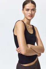 Musculosa en punto acanalado negro, de corte entallado con escote en U pronunciado tanto en el frente como en la espalda.