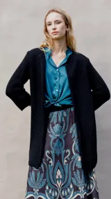 Tapado de punto color negro con textura tipo waffle, corte recto y mangas largas.