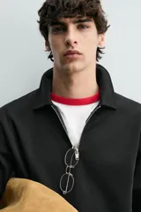 Sudadera polo de corte regular, confeccionada en tejido técnico interlock de algodón con elasticidad. Presenta cuello solapa, cierre frontal de cremallera y manga larga con puños acabados en rib.