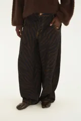 Pantalón de jean tiro alto y corte wide leg, con estampado animal print tipo cebra en tonos marrón y negro. Cuenta con bolsillos laterales y costuras pespunteadas en contraste.