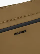 Cartera mensajera color marrón con correa de tela negra con el logo de Tommy Hilfiger. Tiene dos bolsillos con cremallera, uno principal y otro interior.