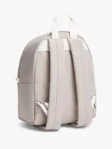 Mochila Tommy Jeans de color beige, diseño compacto y curvo, con compartimento principal con cierre de cremallera, bolsillo frontal con cremallera y parche con el logo de la marca. Cuenta con asas ajustables y acolchadas.