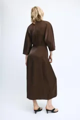 Vestido midi de tejido satinado color marrón, con escote en pico, manga corta y detalle de nudo frontal que genera un efecto drapeado.