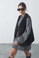 Chaleco de piel sintética negra con textura de borrego, diseño sin mangas y calce relajado. Cuenta con cierre frontal mediante botones y bolsillos laterales.
