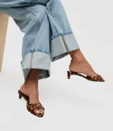 Sandalia tipo mule Satinato con estampado animal print y acabado en pelo corto. Presenta punta redondeada, tacón bajo fino y estructura abierta en el talón.