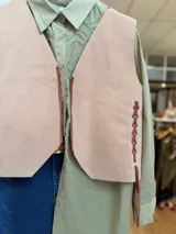 Chaleco artesanal confeccionado en cuero, con diseño de cordones decorativos en el frente y terminaciones rústicas.