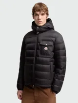 Campera puffer Moncler modelo Ravenlock, color negro, con capucha desmontable, cierre frontal de cremallera y bolsillo en el pecho con solapa y botón a presión con insignia de la marca.