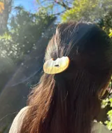 Goma de pelo con elegante pieza decorativa de nácar de forma ovalada, diseñada para aportar un toque sofisticado y único al peinado.