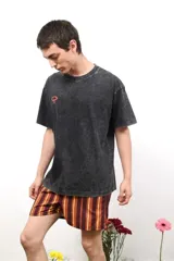 Remera de algodón con efecto acid wash en color gris oscuro, corte holgado y cuello redondo. Presenta un pequeño logo estampado en color rojo en el pecho.