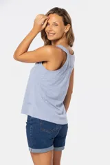 Musculosa blanca sin mangas, de corte clásico y calce cómodo, confeccionada en tejido suave. Presenta escote redondo, cartera con botones frontales y un pequeño bolsillo aplicado en el pecho.