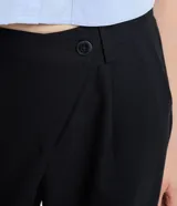 Pantalón de vestir negro, de corte recto, con cintura asimétrica y cierre por botón y cremallera.