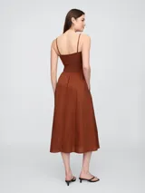 Vestido midi con diseño bicolor, presenta un cuerpo ajustado en color beige con breteles finos negros y una falda amplia de corte evasé en color negro con bolsillos laterales.