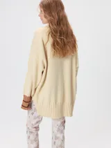 Pullover de punto color rojo, con cuello tortuga, corte holgado y mangas largas con puños acanalados en contraste con rayas blancas. Presenta un logo bordado en el pecho.