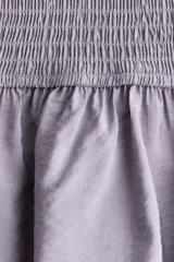 Vestido corto lila de tejido fruncido, con diseño ajustado, hombros descubiertos, escote cuadrado elástico y volados anchos en el escote y en el ruedo.