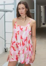 Vestido corto de satén con estampado de camuflaje en tonos rosados, rojos y beige. Presenta un corte amplio tipo A, breteles finos regulables y espalda cavada.