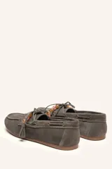 Mocasín estilo náutico de gamuza marrón, con cordones de cuero, borla decorativa y cuentas de colores en el empeine.
