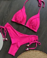 Conjunto de bikini fucsia, con corpiño triangular con detalle de frunce en el centro y bombacha con lazos laterales con detalle de cuentas.
