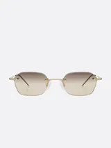 Lentes de sol Carolina Lemke con marco dorado y lentes degradadas de marrón a transparente.