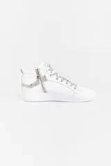 Zapatilla de caña media confeccionada en cuero vacuno blanco, con detalles de glitter plateado en los laterales y apliques de remaches metálicos. Cuenta con cierre lateral para facilitar el acceso y suela de caucho.