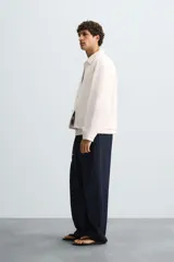 Cazadora de hombre, corte regular fit, color blanco roto, confeccionada en tejido de lino y algodón. Presenta cuello solapa, manga larga con puños abotonados, bolsillos de plastrón en la cadera y cierre frontal de botonadura.