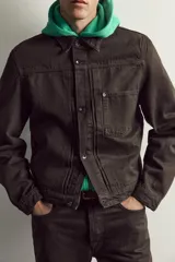 Cazadora cropped fit marrón de denim de algodón, con cuello solapa, manga larga con puño abotonado, bolsillo de parche en el pecho, pliegues verticales en el delantero y cierre frontal con botones.
