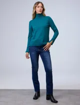 Polera de tejido fino, color rosado, con cuello alto, manga larga y detalle de tajo en los puños.