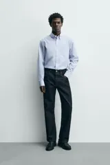 Camisa de corte regular fit confeccionada en tejido de algodón con diseño de rayas verticales finas. Presenta cuello abotonado, manga larga con puños abotonados, bolsillo plastrón en el pecho y cierre frontal con botones.
