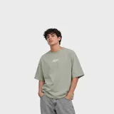 Remera de corte oversize color verde militar, con cuello redondo y pequeño estampado ovalado en el pecho.
