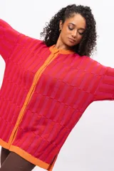 Saco de punto con diseño de bloques de color en tonos rojos y fucsias, con terminaciones en color naranja. Presenta cuello redondo, cierre frontal con botones y mangas largas.