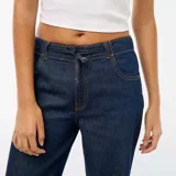 Pantalón de jean con corte baggy y pierna ancha, de tiro medio y color azul oscuro, con cierre frontal y bolsillos laterales.