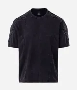Remera boxy de algodón color negro con efecto desteñido, cuello redondo, mangas cortas y hombreras estructuradas con recortes y pespuntes.