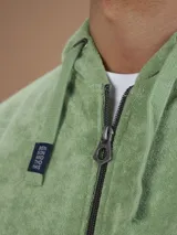 Campera con capucha de toalla color gris claro, con cierre completo y bolsillos frontales.