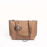 Cartera tipo tote color tostado con textura granulada, doble asa de hombro y monedero circular colgante con estampado animal print.