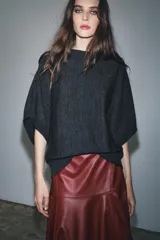 Jersey de punto liso con cuello redondo y mangas cortas anchas. Presenta acabados en rib en el cuello, puños y bajo.