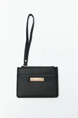 Billetera color mostaza con textura granulada, cierre superior con cremallera y correa de muñeca.