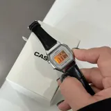 Reloj digital Casio de estilo vintage con caja plateada de 28mm y esfera gris. Cuenta con correa de cuero negro con textura tipo cocodrilo. Incluye funciones de cronómetro, alarma y calendario.