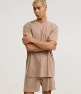 Conjunto de pijama para hombre, compuesto por una remera de manga corta con cuello redondo y un short con cintura elástica y cordón de ajuste. El tejido es de malla flamê con efecto mezcla en tonos beige y marrón.