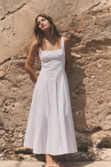 Vestido midi de popelín color blanco, con escote cuadrado y tirantes anchos. Presenta un diseño con godets que aportan volumen a la falda y cierre lateral con cremallera oculta.