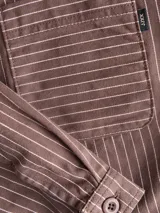 Sobrecamisa marrón con rayas verticales blancas, de corte corto, con cuello clásico, cierre frontal con botones y un bolsillo aplicado en el pecho.