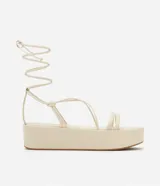 Sandalias flatform color crema, con tiras finas y plataforma plana. Presentan tiras largas para atar alrededor del tobillo.