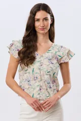 Camisa de lino estampada con diseño floral en tonos lila y verde, mangas cortas con volados y cierre frontal con botones.