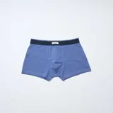 Pack de tres bóxers para hombre en tonos azules. Incluye un modelo azul marino con estampado geométrico de rombos pequeños, un modelo liso en tono azul medio y un modelo a rayas horizontales finas en tonos azul marino y celeste. Todos cuentan con cintura elástica con una pequeña etiqueta central.