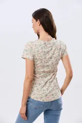Remera de manga corta con cuello redondo, confeccionada en algodón con estampa de diseño floral en tonos rosados y verdes sobre base beige.