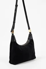 Cartera tipo hobo de Lolita, confeccionada en gamuza color bordó, con diseño de asa integrada y cierre superior. Presenta detalles en cuero liso en los extremos del asa y logo de la marca grabado en el frente.
