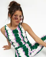 Top sin mangas de cuello redondo y corte halter, confeccionado en tela crepe con estampado geométrico de bloques en tonos verde, lila y blanco. Cuenta con cierre lateral y abertura con botón en la espalda.