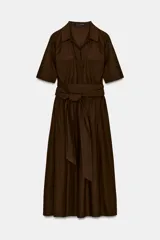 Vestido camisero midi color azul marino, con cuello solapa, escote pico y manga corta con vuelta. Presenta bolsillos laterales ocultos, solapas decorativas en el pecho, cinturón de lazo en el mismo tejido y cierre frontal con botones.