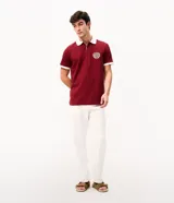 Remera polo azul marino con cuello y puños en contraste de color blanco, manga corta y cierre frontal parcial. Presenta un escudo bordado en el pecho.